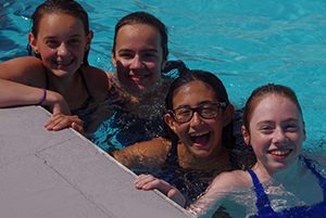 Summer swim team girls in pool, laughing