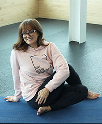 Female yoga instructor sitting with crossed legs on blue mat