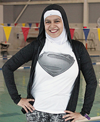Female fitness instructor standing in front of a swimming pool wearing a head cover