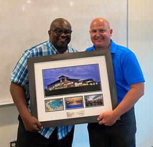 Yemi Akindoju and Jeff McKinnon holding large commemorative frame of CGC photos